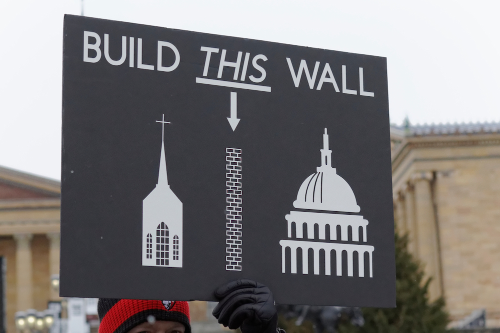 A Women's March demonstrator holds up a sign mocking Donald Trump's border wall and supporting separation of church and state.
