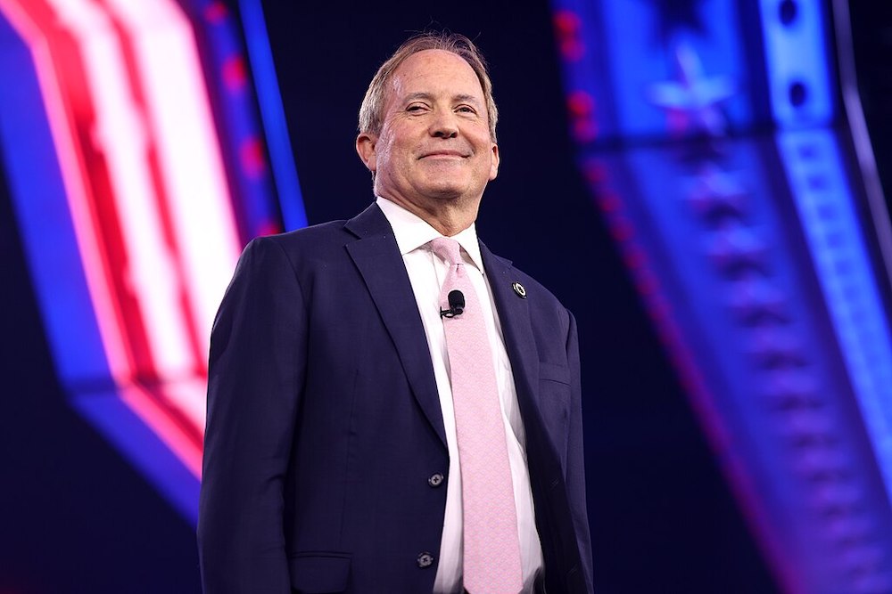Texas Attorney General Ken Paxton smirks from the stage at the 2024 AmericaFest in Phoenix, Arizona.